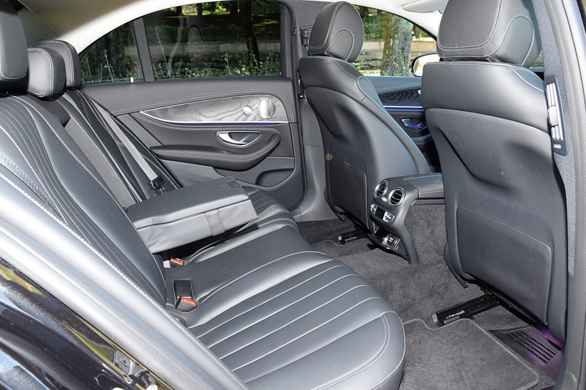 Close-up of the rear passenger area in a Mercedes-Benz luxury sedan, showing two individual leather seats with generous legroom.