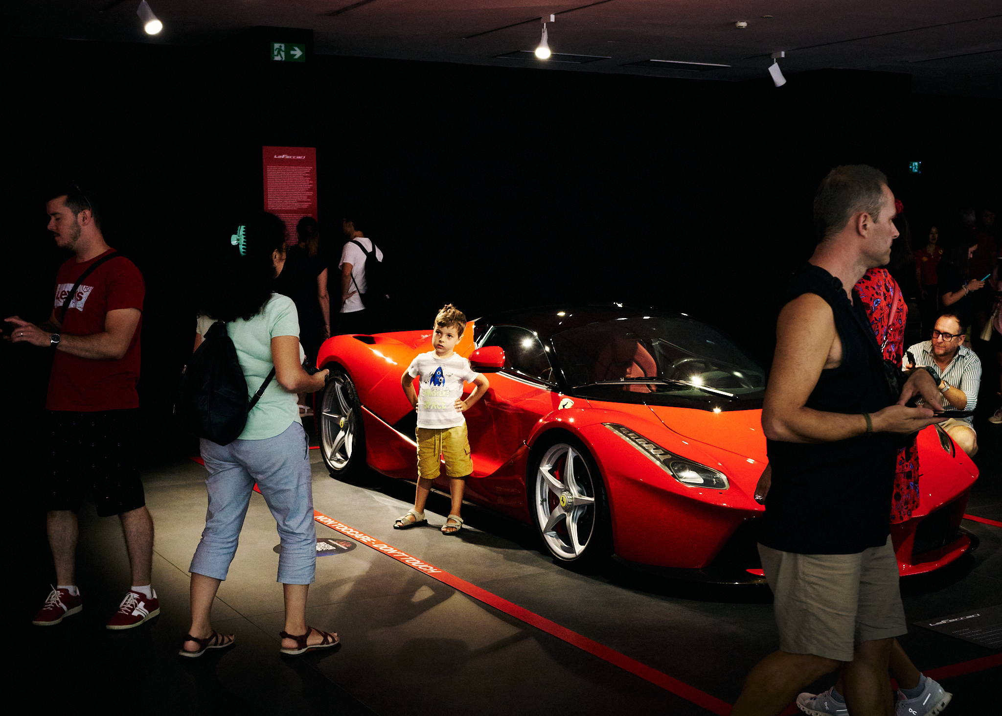 Child standing in front of a Ferrari symbolizing Italian excellence and luxury private transfers from Florence to Pisa