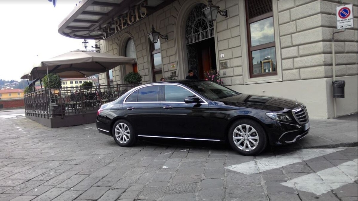 Black Mercedes E-Class sedan parked at the entrance of a luxury hotel in Florence for executive transfer and business class taxi service