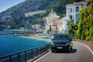 Luxury Mercedes V-Class minivan on a scenic road of the Amalfi Coast. Florence Pisa Taxi for comfortable long distance transfers across Italy.