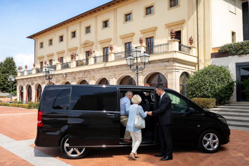 Professional driver from Florence Pisa Taxi assisting guests with luggage at the entrance of a hotel in San Casciano dei Bagni, ready for a comfortable transfer.