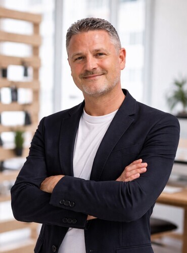 Founder of FlorencePisa.Taxi, professional private chauffeur since 2004, portrait in modern office setting with arms crossed.